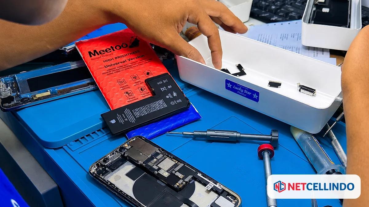 Baterai pengganti dan mesin HP terbuka di meja servis NET CELLINDO