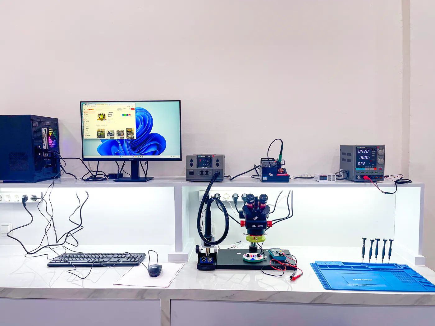 Meja kerja teknisi NET CELLINDO Banjarmasin dengan mikroskop, solder station, dan power supply