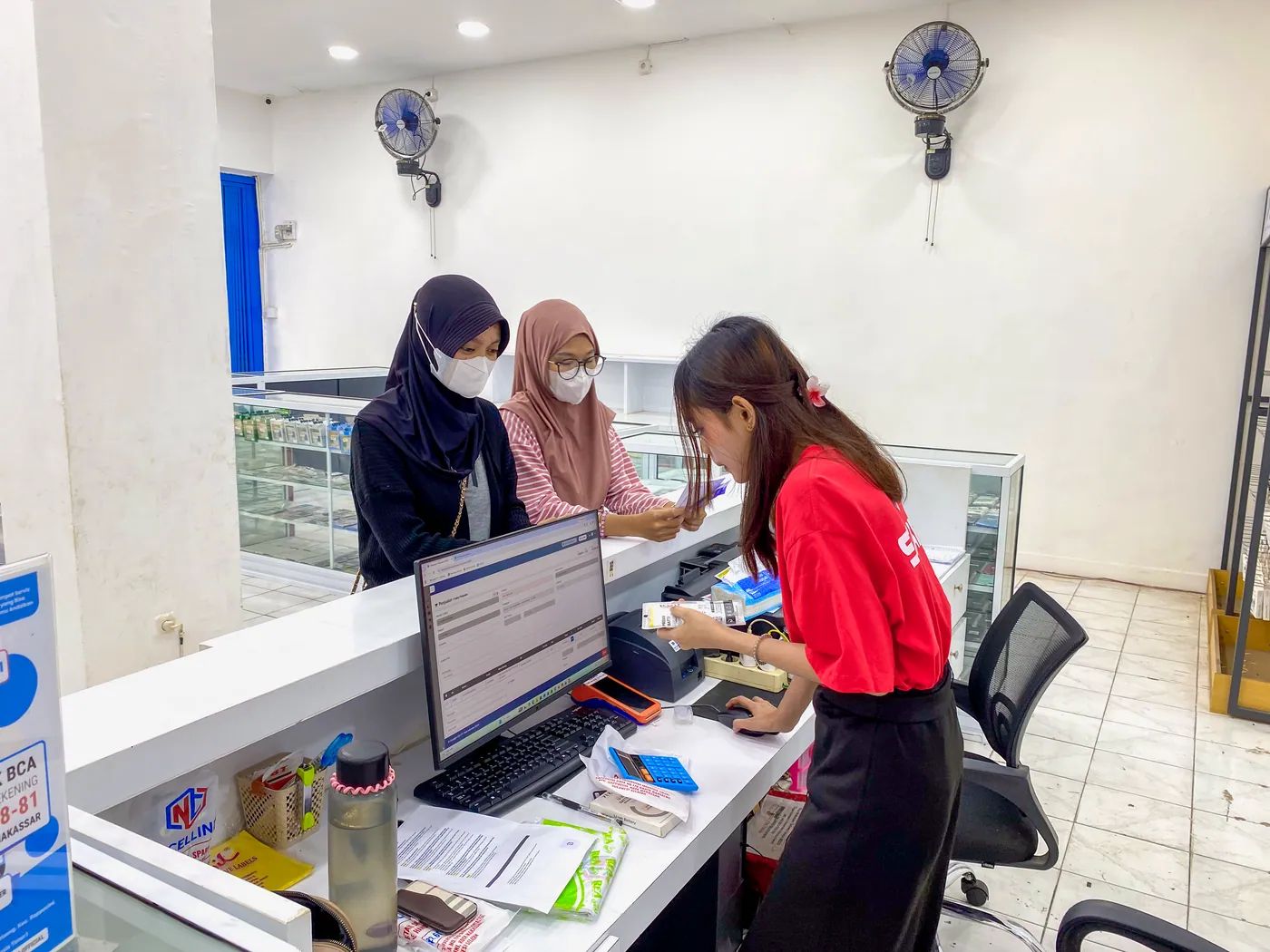 Staf NET CELLINDO Makassar melayani pelanggan di meja penerimaan HP