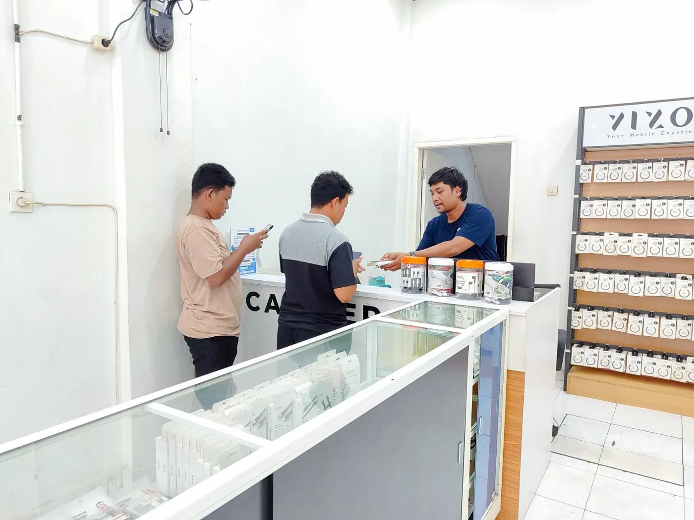Staf NET CELLINDO Medan melayani pelanggan di meja penerimaan HP