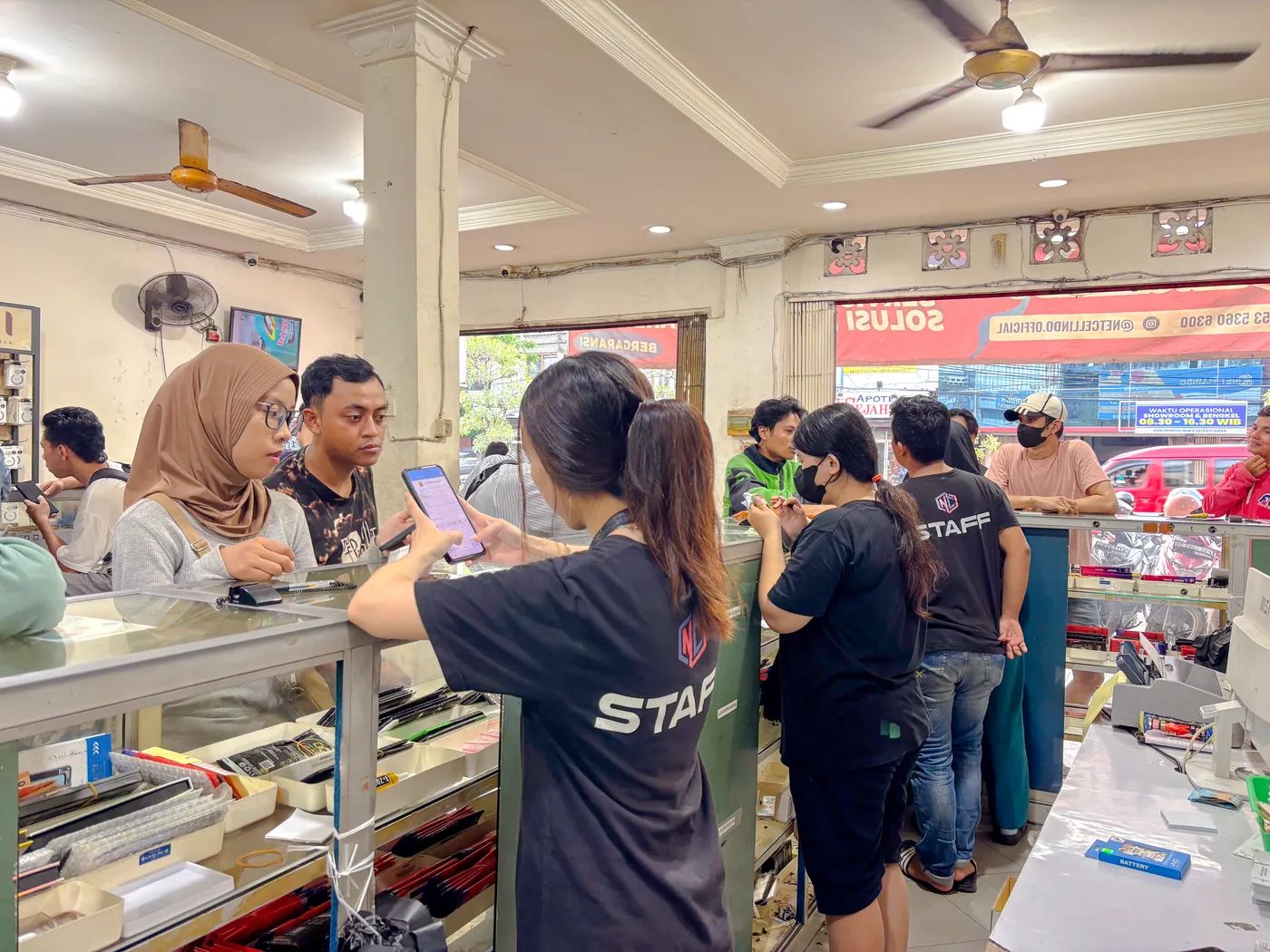 Staf NET CELLINDO Palembang melayani pelanggan di meja penerimaan HP