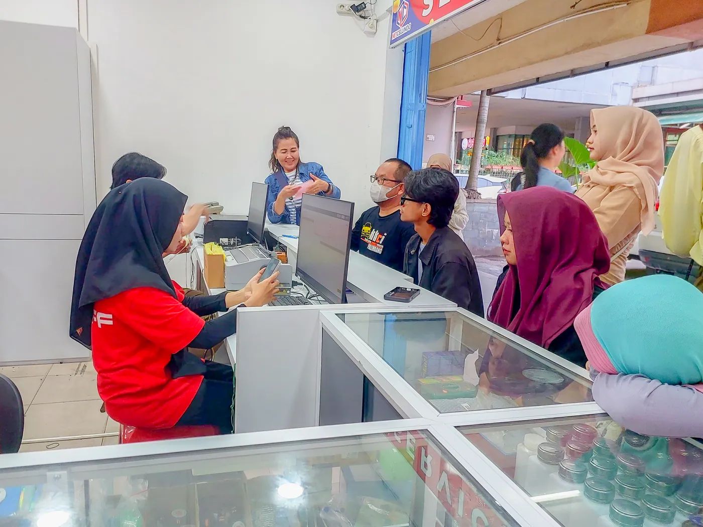 Staf NET CELLINDO Palembang PS melayani pelanggan di meja penerimaan HP