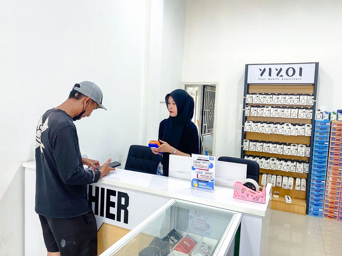 Staf NET CELLINDO Palembang melayani pelanggan di meja penerimaan HP