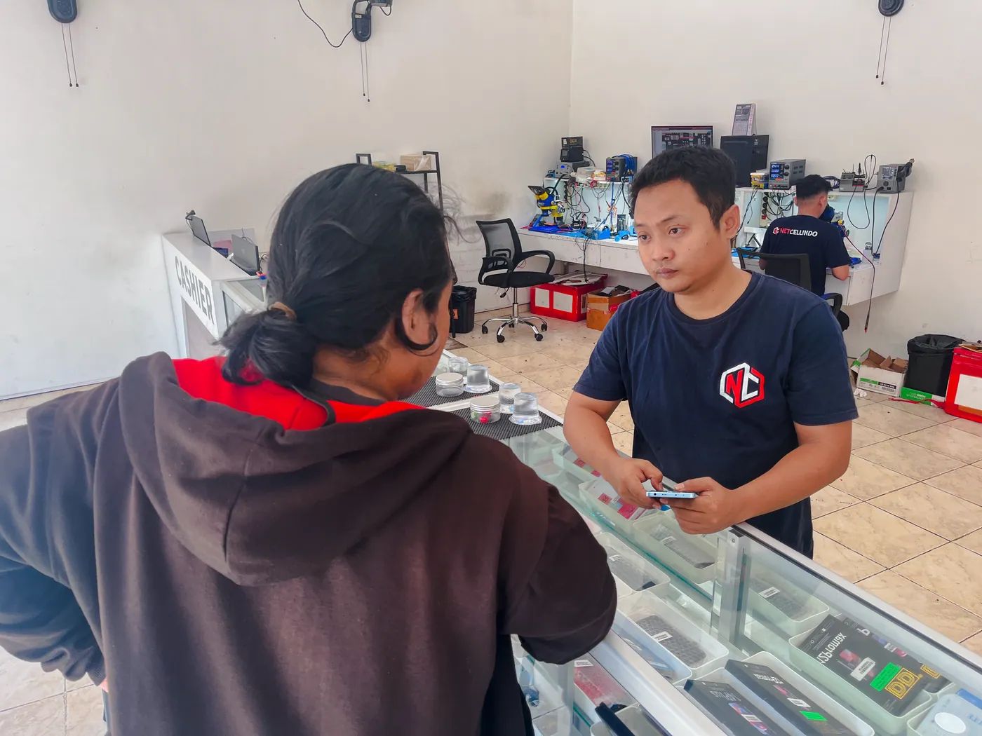 Staf NET CELLINDO Surabaya melayani pelanggan di meja penerimaan HP