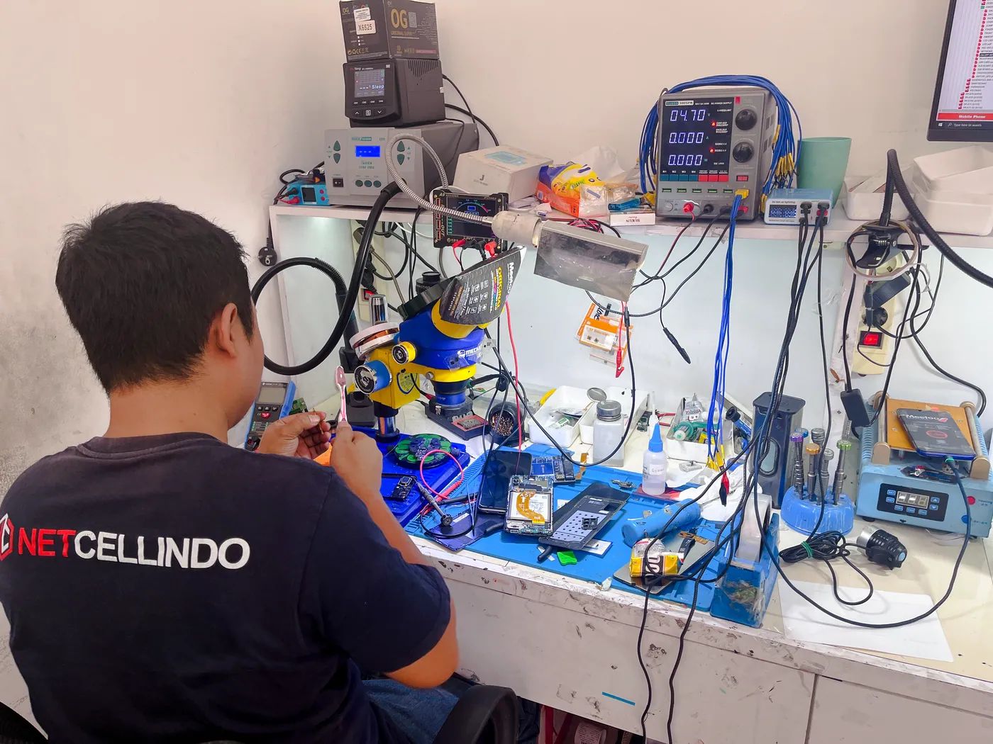 Teknisi NET CELLINDO Surabaya memperbaiki HP dengan peralatan profesional