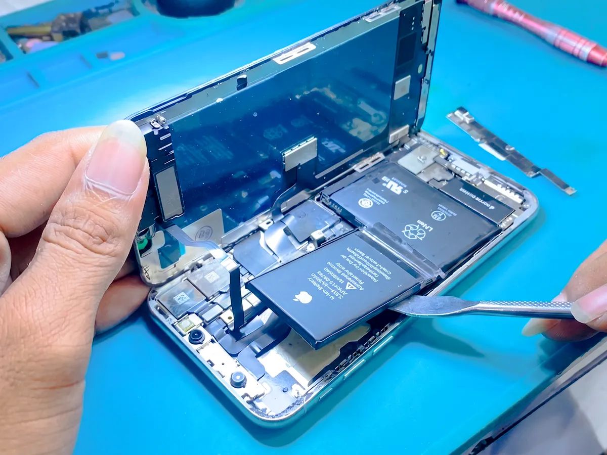 Teknisi NET CELLINDO melepas baterai iPhone dengan alat khusus dari dekat