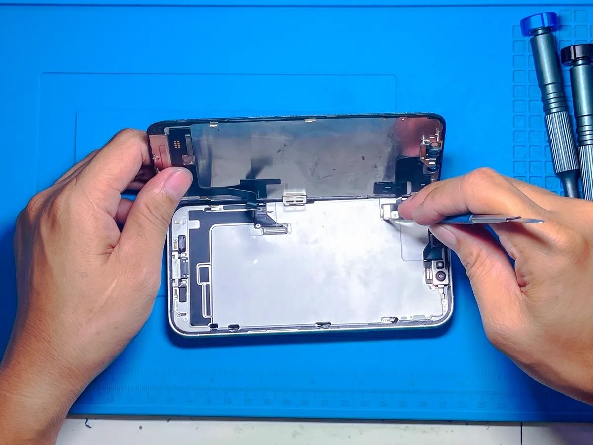 Teknisi NET CELLINDO melepas panel layar iPhone dari rangka dengan alat presisi