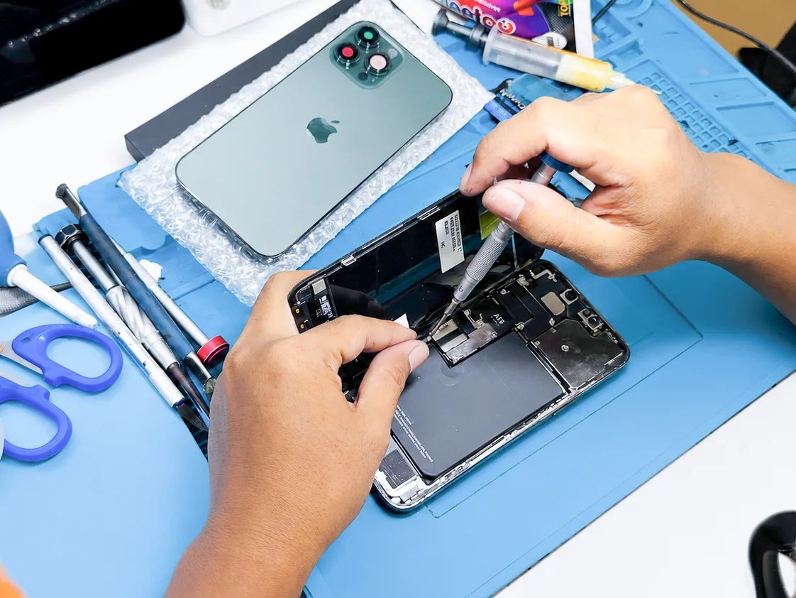 Teknisi NET CELLINDO membongkar iPhone di meja kerja untuk perbaikan
