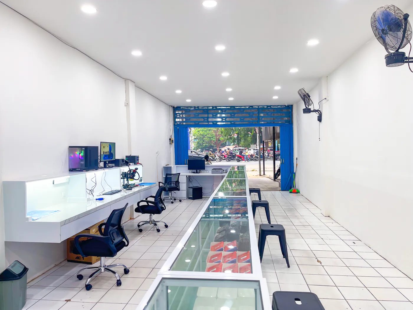 Interior toko NET CELLINDO Banjarmasin: meja teknisi di sisi kiri dan etalase sparepart memanjang sampai pintu depan